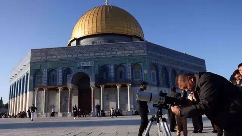 Seorang pria menggunakan teleskop saat mencari bulan sabit untuk menandai dimulainya bulan suci Ramadan di kompleks Masjid Al-Aqsa, Yerusalem, pada 28 Februari 2025. (Dok. AFP)