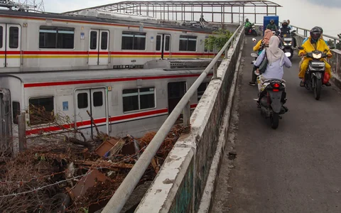 Pengendara motor melewati tumpukan gerbong kereta rel listrik (KRL) bekas di Jalan Kampung Rawageni, Cipayung, Kota Depok, Selasa (20/01/2026).