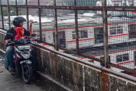 Pengendara motor melihat  tumpukan gerbong kereta rel listrik (KRL) bekas di Jalan Kampung Rawageni, Cipayung, Kota Depok, Selasa (20/01/2026).