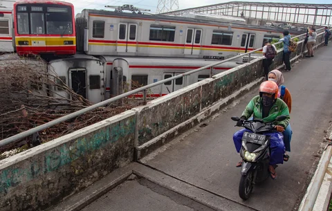 Pengendara motor melewati tumpukan gerbong kereta rel listrik (KRL) bekas di Jalan Kampung Rawageni, Cipayung, Kota Depok, Selasa (20/01/2026).