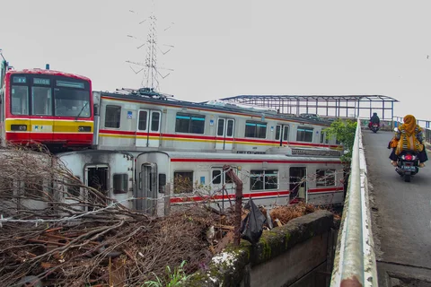 Pengendara motor melewati tumpukan gerbong kereta rel listrik (KRL) bekas di Jalan Kampung Rawageni, Cipayung, Kota Depok, Selasa (20/01/2026).