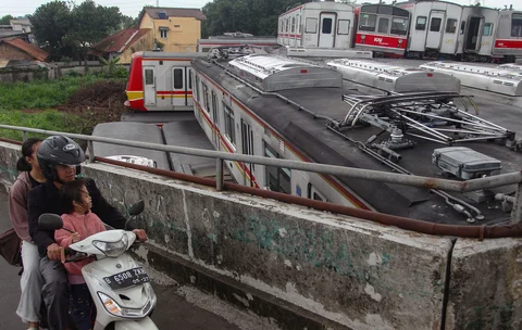 Pengendara motor melewati tumpukan gerbong kereta rel listrik (KRL) bekas di Jalan Kampung Rawageni, Cipayung, Kota Depok, Selasa (20/01/2026).