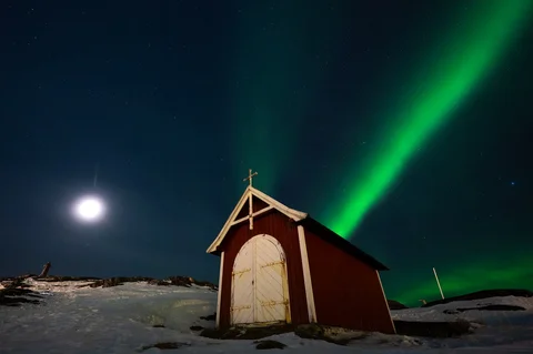 Aurora borealis menerangi langit malam di atas rumah-rumah penduduk di Nuuk, Greenland, Jumat (23/01/2026) waktu setempat.
