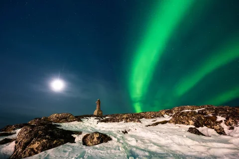 Aurora borealis menerangi langit malam di atas rumah-rumah penduduk di Nuuk, Greenland, Jumat (23/01/2026) waktu setempat.