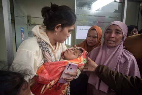 Seorang wanita menggendong anak laki-laki yang selamat dari tanah longsor di desa Pasirlangu, Bandung, Jawa Barat, Sabtu (24/01/2026).