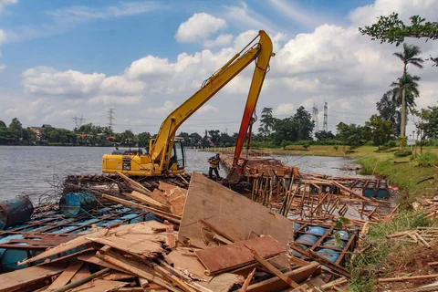 Petugas Dinas Sumber Daya Air Pemprov Jawa Barat membongkar tiang pancang beton yang dipasang di Setu Tujuh Muara, Sawangan, Depok, Senin (16/01/2026).