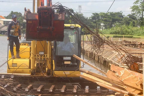 Petugas Dinas Sumber Daya Air Pemprov Jawa Barat membongkar tiang pancang beton yang dipasang di Setu Tujuh Muara, Sawangan, Depok, Senin (16/01/2026).
