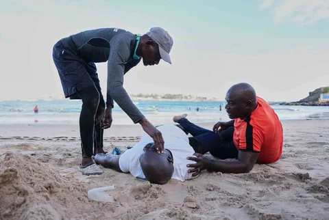Instruktur membantu seorang peserta berolahraga di tepi pantai di Dakar, Senegal, Sabtu (06/12/2025).