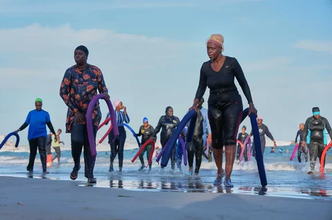 Para peserta berjalan keluar dari laut setelah sesi terapi air kelompok di Dakar, Senegal, Sabtu (06/12/2025).