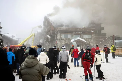 Orang-orang menyaksikan petugas pemadam kebakaran memadamkan kebakaran hebat di hotel bintang lima Grandes Alpes di resor ski elite Courchevel, Alpen Prancis, Rabu (28/1/2026).