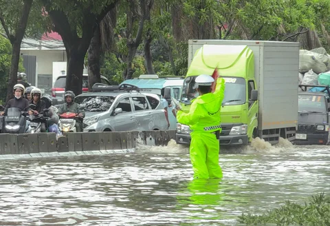Petugas polantas mengatur arus lalu lintas kendaraan bermotor yang menerobos banjir di ruas Jalan Daan Mogot, Jakarta, Kamis (29/1/2026).