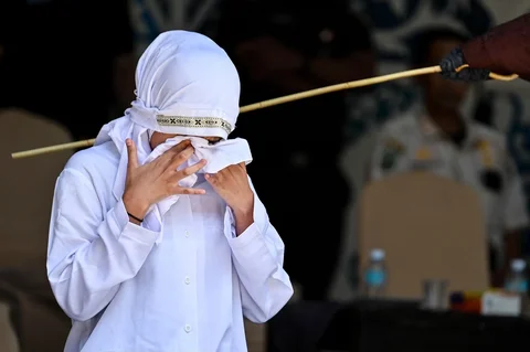 Seorang wanita bereaksi saat dicambuk di depan umum oleh anggota polisi Syariah di Banda Aceh, Kamis (29/01/2026).