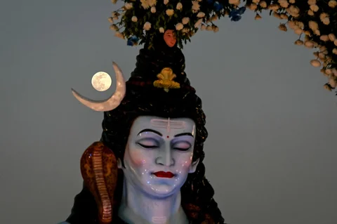 Bulan terbit di samping patung dewa Hindu Siwa di Ahmedabad, India, Jumat (02/01/2026).