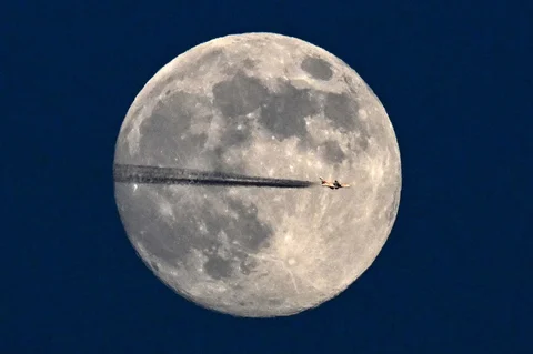 Sebuah jet terbang melintasi bulan purnama Januari, yang juga dikenal sebagai "Bulan Serigala", di atas Frankfurt am Main, Jerman, , Jumat (02/01/2026).