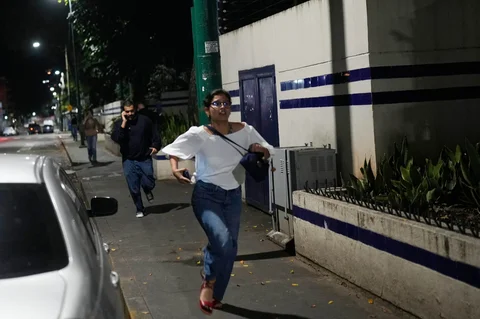 Para pejalan kaki berlari setelah terdengar ledakan dan pesawat terbang rendah di Caracas, Venezuela, Sabtu, (-3/01/2026).
