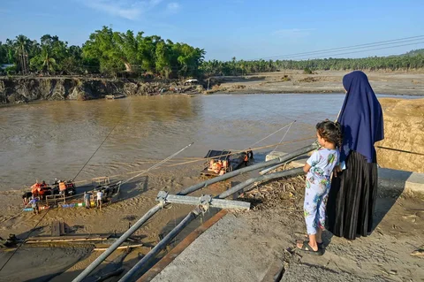 Warga menyaksikan  rakit untuk menyeberangi sungai Peusangan di Ulee Jalan, Peusangan Selatan, Bireuen, Aceh, Senin (05/01/2026).