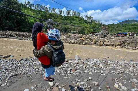 Warga menggunakan tali untuk menyeberangi sungai pascabanjir bandang di Ketol, Aceh, Selasa (06/01/2026).