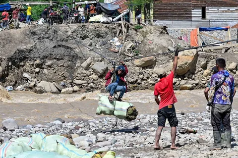 Warga menggunakan tali untuk menyeberangi sungai pascabanjir bandang di Ketol, Aceh, Selasa (06/01/2026).