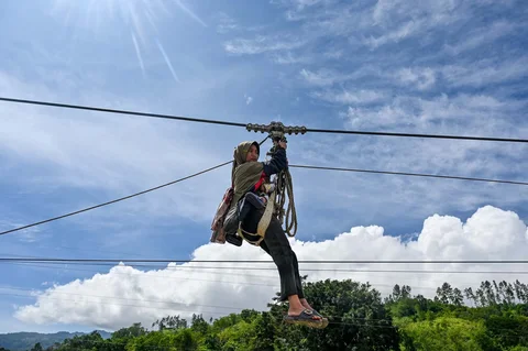 Warga menggunakan tali untuk menyeberangi sungai pascabanjir bandang di Ketol, Aceh, Selasa (06/01/2026).