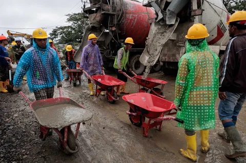 Para pekerja mengangkut beton dengan gerobak dorong saat pembangunan unit perumahan sementara yang dibangun oleh Danantara, di Aceh Tamiang, Aceh, Kamis (08/01/2026).