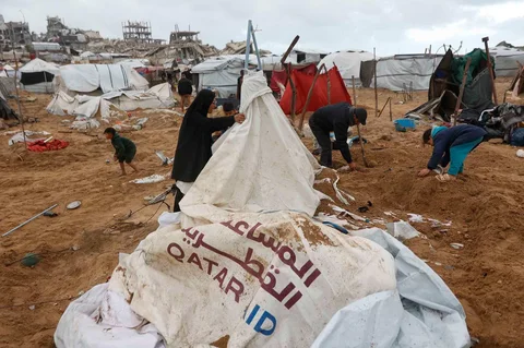 Seorang wanita Palestina membersihkan pasir dari terpal tenda, sehari setelah militer Israel menembaki kamp tenda yang menampung keluarga pengungsi, di kamp pengungsi Al-Shati, Gaza, Palestina,  Jumat (09/01/2026).
