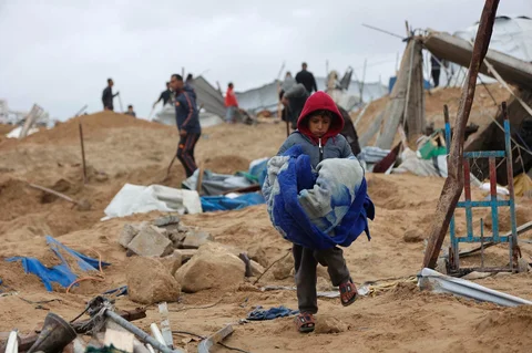 Seorang anak Palestina menyelamatkan beberapa barang miliknya, sehari setelah militer Israel menembaki kamp tenda yang menampung keluarga pengungsi, di kamp pengungsi Al-Shati, di Kota Gaza, Palestina,  Jumat (09/01/2026).