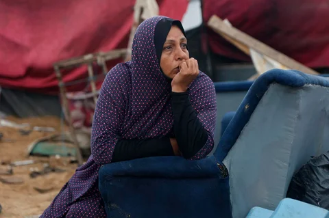 Seorang wanita Palestina duduk menyaksikan orang lain mengatur kembali tenda-tenda penampungan mereka, sehari setelah militer Israel menembaki kamp tenda yang menampung keluarga pengungsi, di kamp pengungsi Al-Shati, di Kota Gaza,  Palestina,  Jumat (09/01/2026).