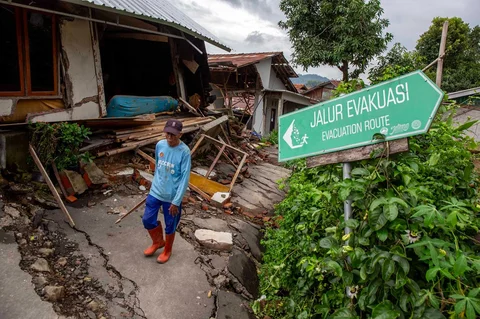Warga  berjalan melewati rumah yang rusak akibat  fenomena  tanah bergerak di desa Padasari di Tegal, Jawa Tengah, Senin (09/02/2026).