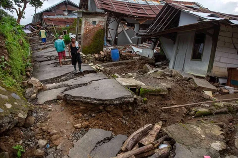 Warga  berjalan melewati rumah yang rusak akibat  fenomena  tanah bergerak di desa Padasari di Tegal, Jawa Tengah, Senin (09/02/2026).