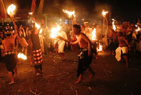 Warga dipukul dengan daun kelapa kering yang dibakar saat ritual Lukat Geni atau perang api di desa Paksebali, Klungkung, Bali, Indonesia, 28 Maret 2025.