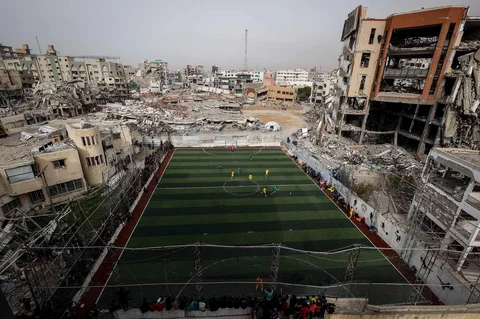 Warga Palestina menyaksikan pertandingan sepak bola lima lawan lima di tengah reruntuhan bangunan yang hancur di Kota Gaz, Senin (09/02/2026) waktu setempat.