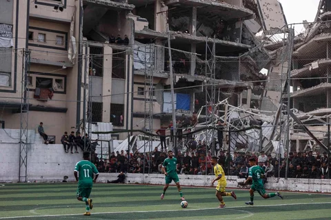 Warga Palestina menyaksikan pertandingan sepak bola lima lawan lima di tengah reruntuhan bangunan yang hancur di Kota Gaz, Senin (09/02/2026) waktu setempat.