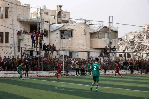 Warga Palestina menyaksikan pertandingan sepak bola lima lawan lima di tengah reruntuhan bangunan yang hancur di Kota Gaz, Senin (09/02/2026) waktu setempat.