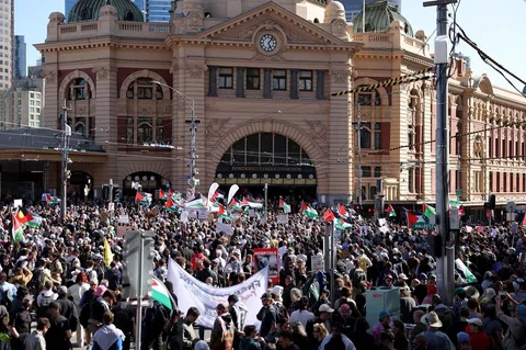 Para pengunjuk rasa memegang bendera dan spanduk di luar stasiun Flinders Street di Melbourne, Australia, Kamis (12/02/2028).