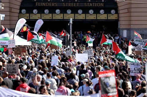 Para pengunjuk rasa memegang bendera dan spanduk di luar stasiun Flinders Street di Melbourne, Australia, Kamis (12/02/2028).