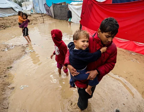 Anak-anak berjalan menlitasi banjir  di kamp pengungsi Maghazi di Jalur Gaza tengah, Selasa, (25/11/2025).