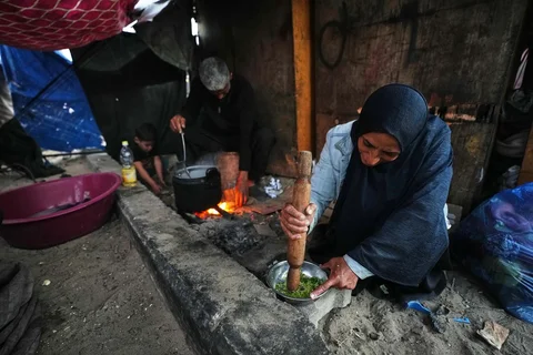 Warga Palestina yang mengungsi, Camellia Al-Zamli, dan suaminya Walid Al-Zamli menyiapkan makanan untuk iftar keluarga mereka, yaitu hidangan berbuka puasa, pada hari pertama Ramadan di Khan Younis, Jalur Gaza, Rabu (18/02/2026).