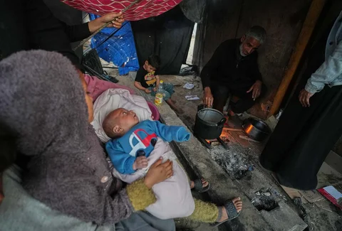 Warga Palestina yang mengungsi, Camellia Al-Zamli, dan suaminya Walid Al-Zamli menyiapkan makanan untuk iftar keluarga mereka, yaitu hidangan berbuka puasa, pada hari pertama Ramadan di Khan Younis, Jalur Gaza, Rabu (18/02/2026).