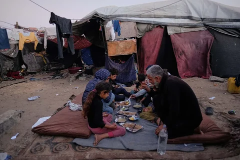Warga Palestina yang mengungsi, Camellia Al-Zamli bersama suaminya Walid Al-Zamli, saat menikmati  hidangan berbuka puasa keluarga mereka pada hari pertama Ramadan di depan tenda pengungsian di Khan Younis, Jalur Gaza, Rabu (18/02/2026).
