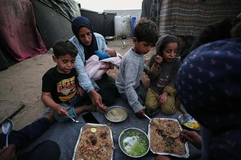 Warga Palestina yang mengungsi, Camellia Al-Zamli bersama suaminya Walid Al-Zamli, saat menikmati  hidangan berbuka puasa keluarga mereka pada hari pertama Ramadan di depan tenda pengungsian di Khan Younis, Jalur Gaza, Rabu (18/02/2026).