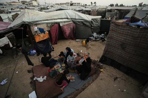 Warga Palestina yang mengungsi, Camellia Al-Zamli bersama suaminya Walid Al-Zamli, saat menikmati  hidangan berbuka puasa keluarga mereka pada hari pertama Ramadan di depan tenda pengungsian di Khan Younis, Jalur Gaza, Rabu (18/02/2026).