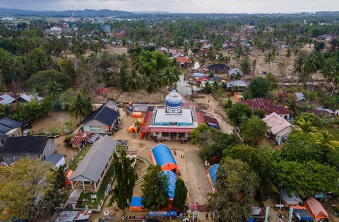 Foto udara memperlihatkan tenda-tenda darurat berwarna oranye dan biru yang didirikan di kompleks masjid di Meurah Dua, Pidie Jaya, Aceh,Sabtu (21/02/2026), sebagai tempat tinggal sementara bagi korban banjir dan tanah longsor dahsyat yang melanda Sumatra akhir tahun lalu.
