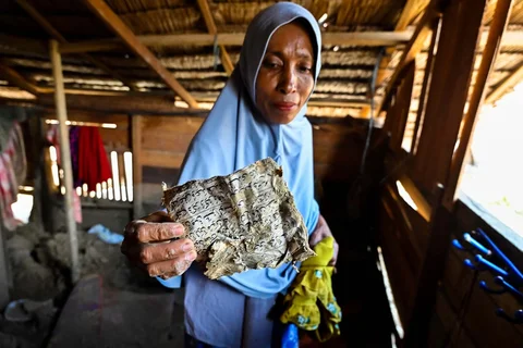 Rauzah, seorang ibu empat anak yang selamat dari banjir, memegang halaman kotor dari buku 'Iqra' yang digunakan anak-anak untuk belajar membaca Al-Quran, di rumahnya yang rusak di Meurah Dua, distrik Pidie Jaya, provinsi Aceh, Minggu (22/02/2026).