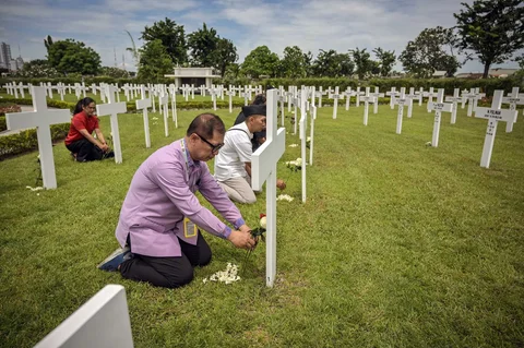 Warga meletakkan bunga Mawar di makam saat prosesi peringatan Pertempuran Laut Jawa di Ereveld (Makam Kehormatan) Kembang Kuning, Surabaya, Jawa Timur, Jumat (27/2/2026).