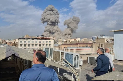 Orang-orang menyaksikan asap mengepul di cakrawala setelah ledakan di Teheran, Iran, Sabtu (28/02/2026).