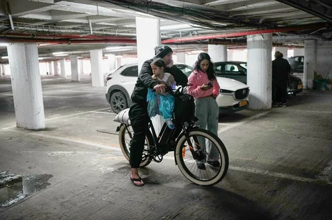 Sepasang suami istri bersama anak mereka berdiri di tempat parkir bertingkat yang digunakan sebagai tempat berlindung setelah sirene peringatan berbunyi menyusul serangan Israel terhadap Iran, di Tel Aviv, Israel, Sabtu (28/02/2026).
