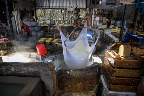 Seorang pekerja menyaring kedelai giling yang sudah dimasak untuk mendapatkan ekstraknya di pabrik tahu di kawasan Dinoyo, Surabaya, Kamis (05/02/2026).
