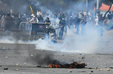 Umat Muslim Syiah melemparkan kembali selongsong gas air mata yang ditembakkan polisi untuk membubarkan mereka di dekat Konsulat AS di Karachi, Pakistan, Minggu, (01/03/2026).