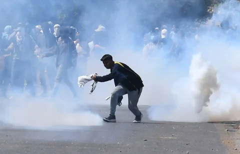 Umat Muslim Syiah berlari mencari perlindungan setelah polisi menembakkan gas air mata untuk membubarkan mereka di dekat Konsulat AS di Karachi, Pakistan, Minggu, (01/03/2026).