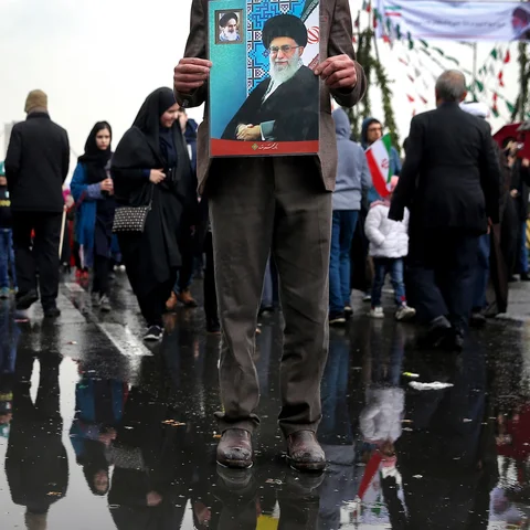 Seorang pria memegang poster bergambar Pemimpin Tertinggi Iran Ayatollah Ali Khamenei dalam upacara peringatan 40 tahun Revolusi Islam Iran di Teheran, Senin (11/2). (AP Photo/Ebrahim Noroozi)